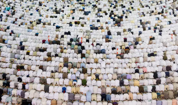 Thousands of crowded people standing together in circle order lines praying in The Holdy Mosque in Mecca, Saudi Arabia