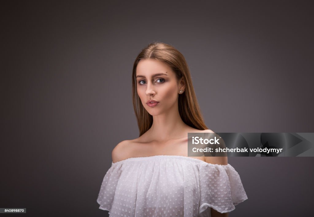 Beautiful girl in white blouse Beautiful girl in white blouse and bare shoulders posing on gray background Activity Stock Photo