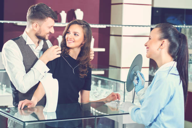 istock Young man helping his girlfriend with fitting necklace at the je 840902180