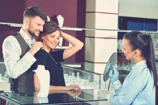istock Young man helping his girlfriend with fitting necklace at the je 840902228