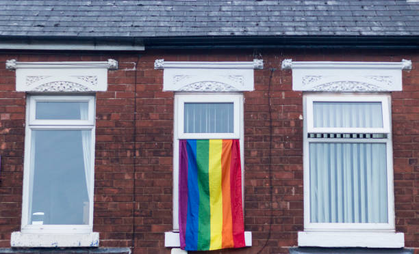 Gay pride LGBTQ flag flying from a house window stock photo
