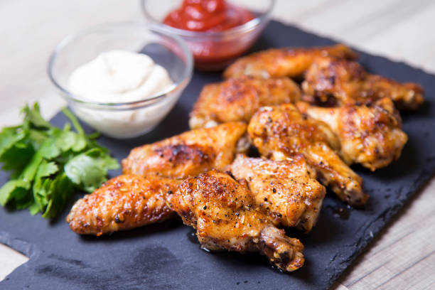 istock Barbecue chicken wings with two sauces on a black board. 840915312