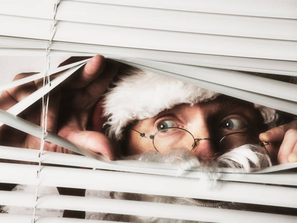 istock Santa Claus peers through the blinds on a window 840917878