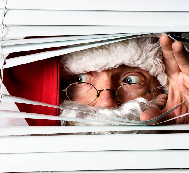 Santa Claus peeking through the blinds on a window