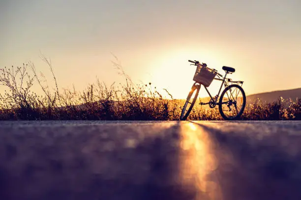Photo of Vintage bike parked on country road at sunset. Copy space.
