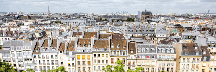 Aerial panoramic cityscape view on the beautiful buildings and Eiffel tower on the horizon during the cloudy weather in Paris