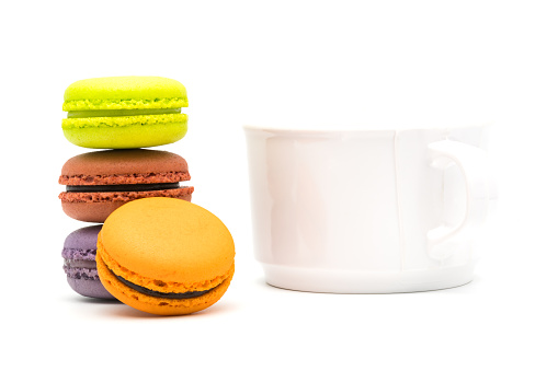 Tower of sweet macarons and a cup of hot tea on white background