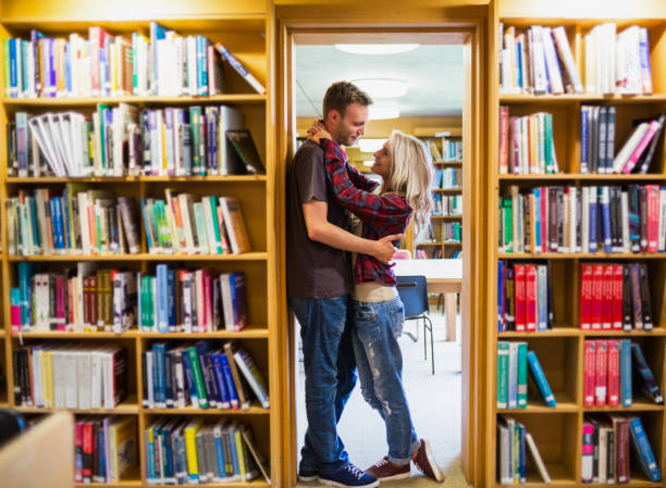 istock Romantic couple embracing by bookshelves in library 840927780