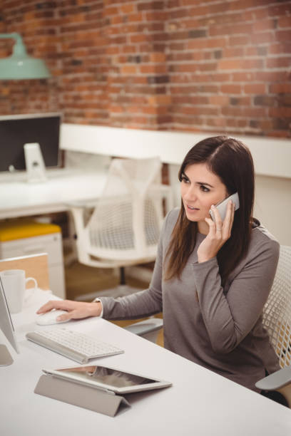 istock Female executive talking on mobile phone at desk 840930696