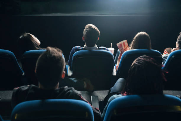 Movies Night Rear view of the spectators in their seats watching movie at the cinema premiere stock pictures, royalty-free photos & images