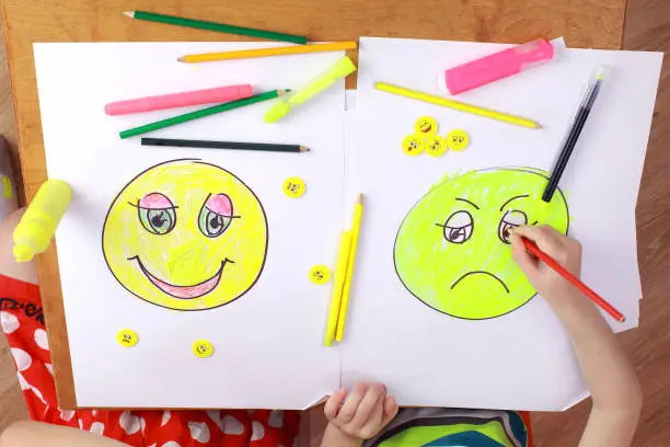 child psychology. girl and boy depict different emotions. the girl and the boy draw happy and sad emoticons