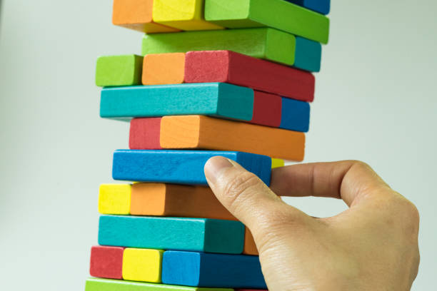 istock Hand pulling colorful wooden block from the tower in as Risk or stability concept 840936780
