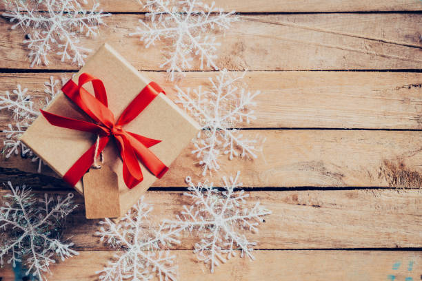 istock Christmas gift boxes placed and white snowflakes on wooden planks with space. 840940278