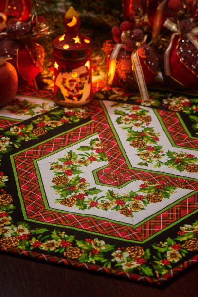 christmas patchwork napkin, blurred christmas candle holder with flaming candle inside and christmas decorations on back view - christmas quilt craft patchwork imagens e fotografias de stock