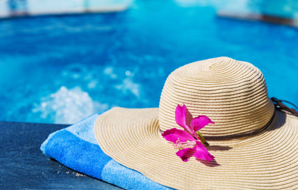 istock Straw hat with orchid flower and blue towel pool 840947294