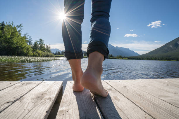 istock Woman's feet on jetty above lake at sunrise 840947496