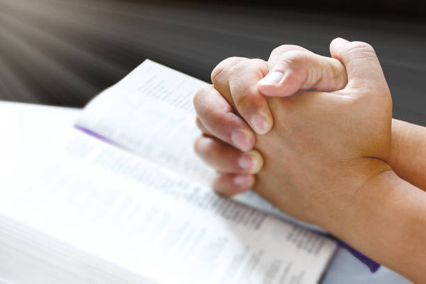 istock Human hands praying on holy bible with light 840948634