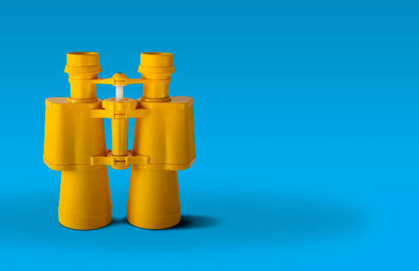 Yellow binoculars Yellow binoculars isolated on  a blue background searching binoculars stock pictures, royalty-free photos & images