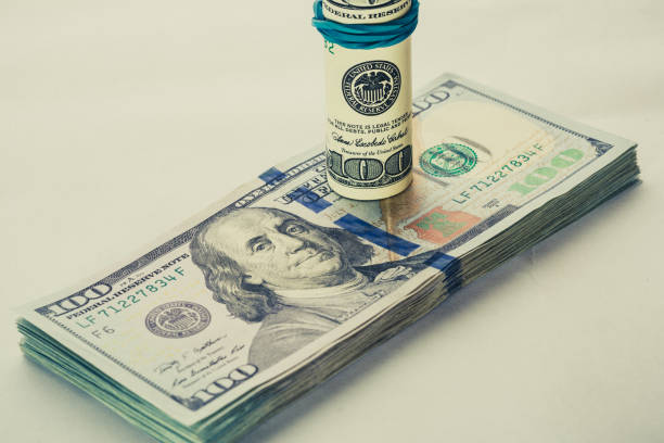 istock A coiled 100 dollar bill which rests on another angled 100 dollar bill isolated on white background 840956782