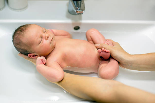 Sweet newborn boy, having his bath in mothers hands Sweet newborn child boy, having his bath in mothers hands, baby calm and peacefully sleeping sponge bath sponge nature animal stock pictures, royalty-free photos & images