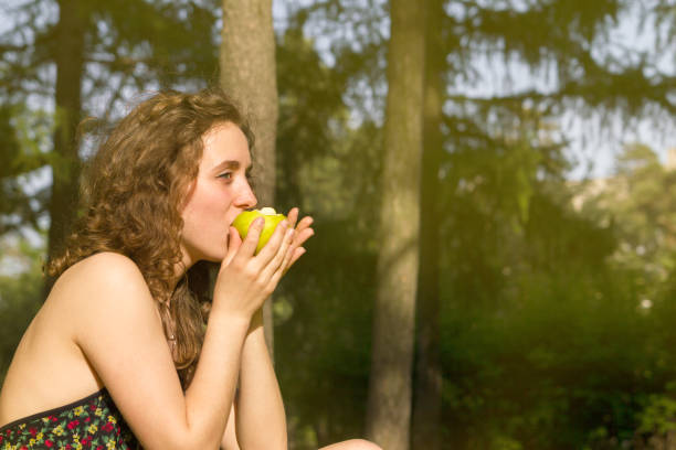 istock Young pretty woman eating apple on a field 840964192