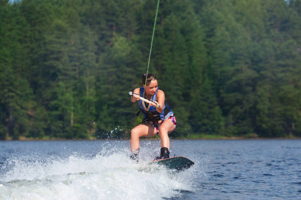 istock slim brunette woman riding wakeboard on lake 840968124