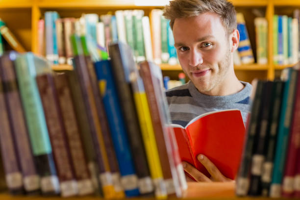 istock Male student reading a book in the library 840968386