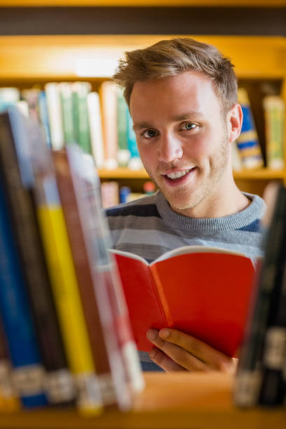 istock Male student reading a book in the library 840968406