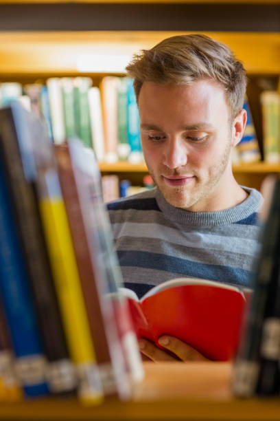 istock Male student reading a book in the library 840968424