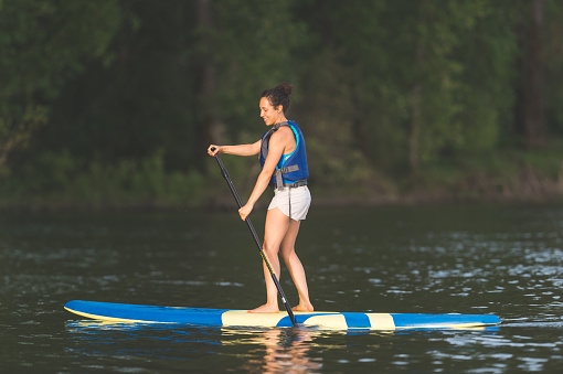 Young Hawaiian woman smiles with delight as she enjoys an afternoon on the river with her standup paddle board