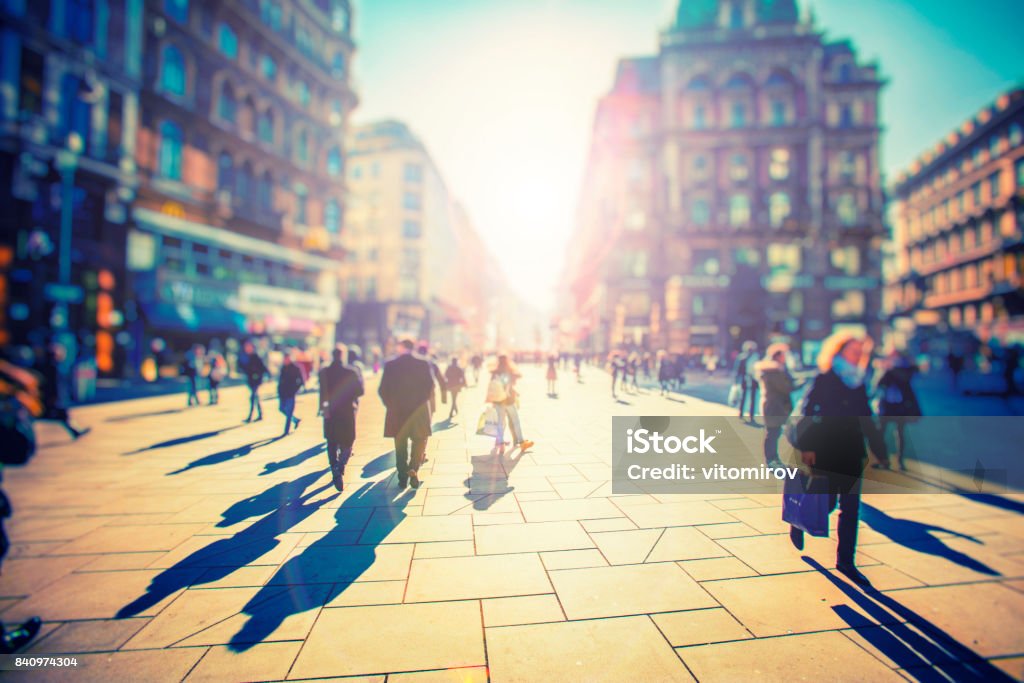 Crowd of anonymous people walking on sunset in the city streets People Stock Photo