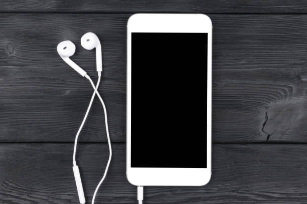 istock Smartphone with headphones on black wooden table. Smartphone with solated screen. Empty space for text. Copy space. Smartphone blank screen. Smartphone mock up. earphone. 840978418