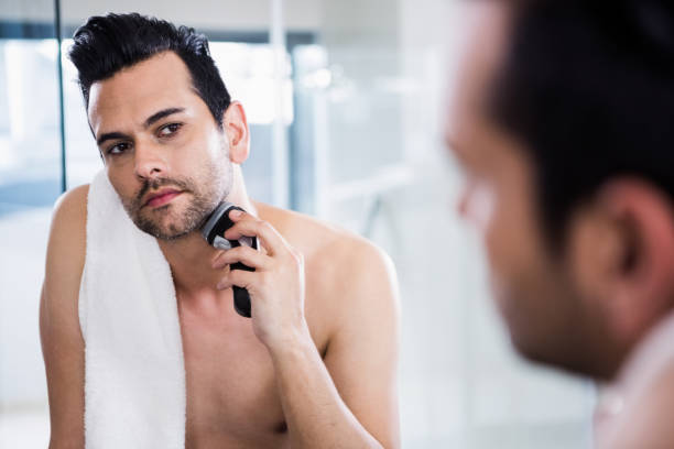 istock Handsome man shaving in the mirror 840989530