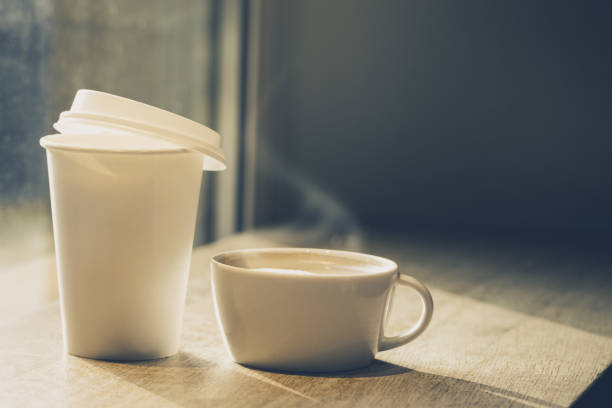 Coffee in ceramic cup and in paper cup to go on table in cafe. Horizontal Toning