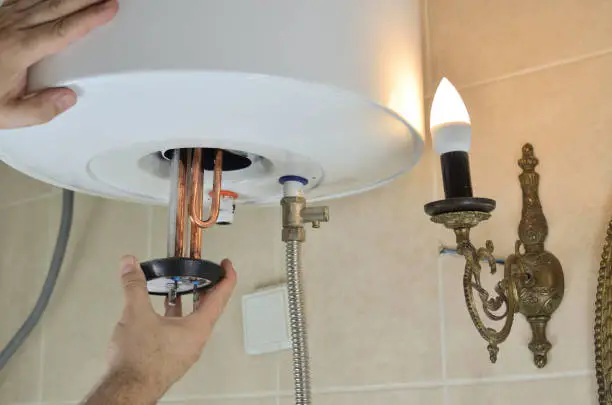 Man's hand installing a new water heater in a boiler