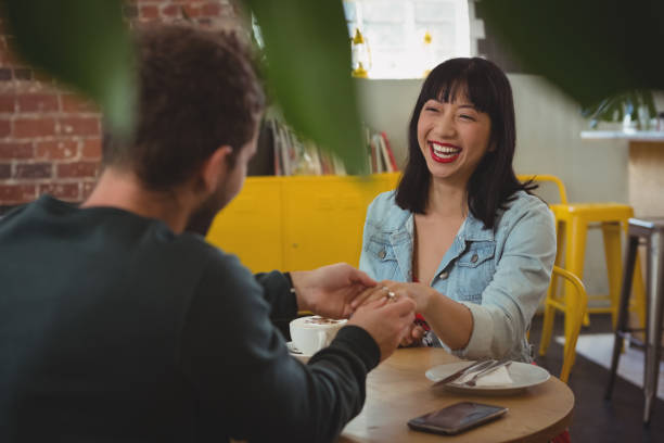 istock Man putting ring on woman finger at cafe 840997820