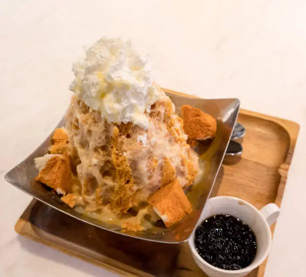 Photo of Thai tea shaved ice topped with whipped cream and white bread by tapioca pearl.