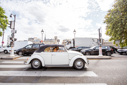 PARIS, FRANCE - August 07, 2017: Young couple driving white retro car in the centre of Paris
