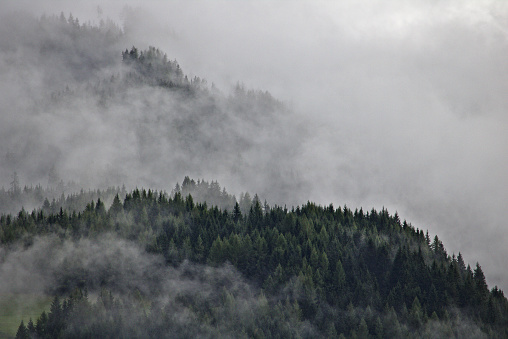 Mountain ridges in the Austrian Alps party obscured by mist and clouds