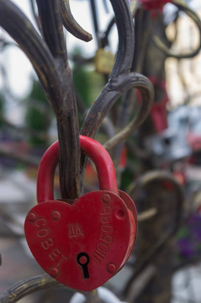 Young spouses in the wedding day close the lock on a tree of love with a wish never to leave. On the case of the lock a wish COUNCIL YES LOVE