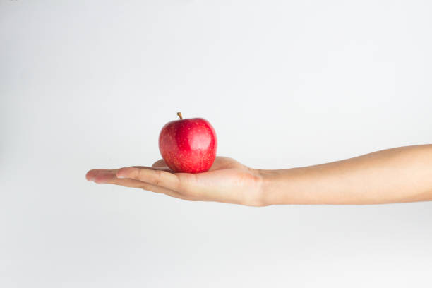 istock close-up view of a hand holding red apple on a white background 841017800