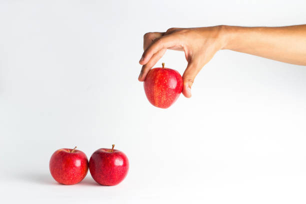 istock close-up view of a hand trying to pick up a red apple 841018332