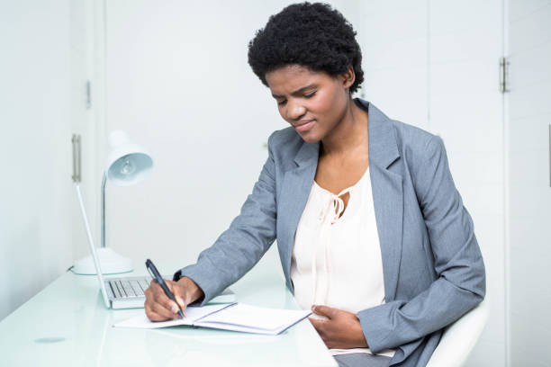 istock Pregnant businesswoman writing on notebook 841026932