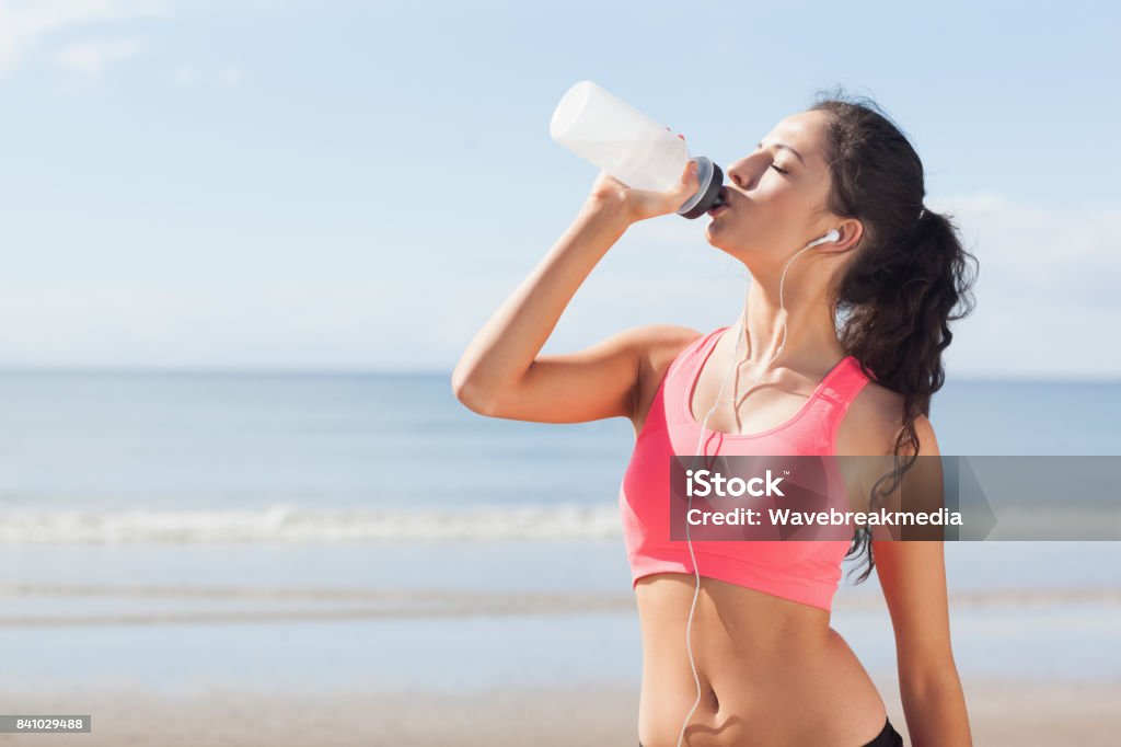 Eau potable saine de belle femme sur la plage - Photo de Brassière de sport libre de droits