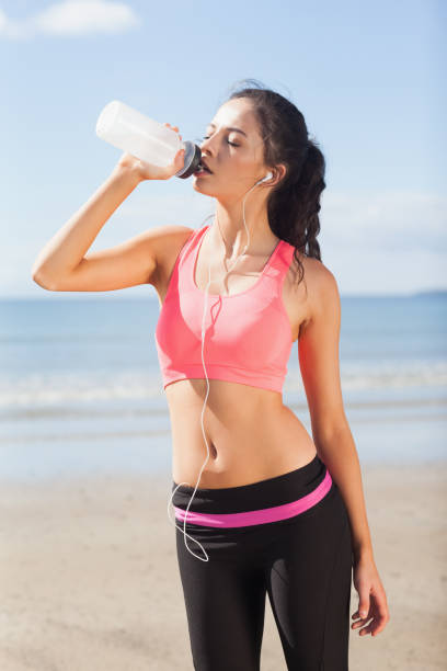 istock Beautiful healthy woman drinking water on beach 841029492