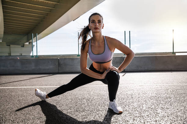 istock Fitness female exercising under a bridge, warming up her legs 841036712