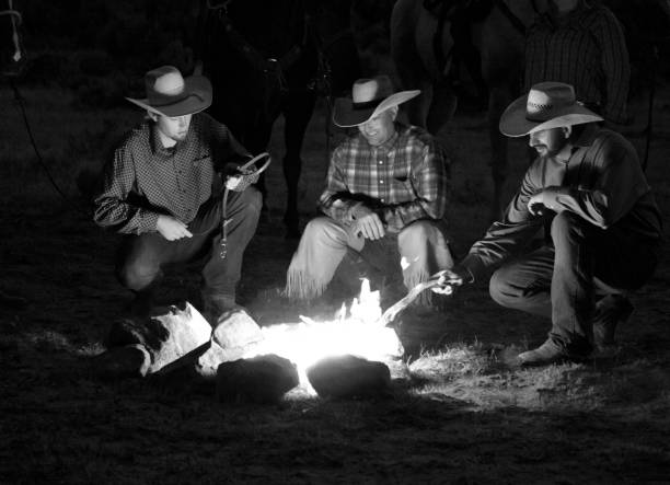 istock monochrome smiling cowboys outdoors at dusk by campfire 841040338