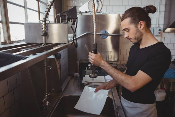 Waiter washing plates in cafe Young waiter washing plates while standing in cafe kitchen dishwasher stock pictures, royalty-free photos & images