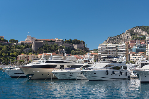 View of the Port Hercules harbour of  Monaco Monte Carlo. In the background overlooking the harbour is the Rock of Monaco where Monaco-Ville, the oldest part of Monaco, and the Prince's Palace can be seen against the skyline of a clear blue sky, together with the many high-rise apartment buildings climbing the hillside