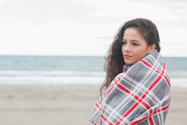 istock Side view of a woman covered with blanket at beach 841042176